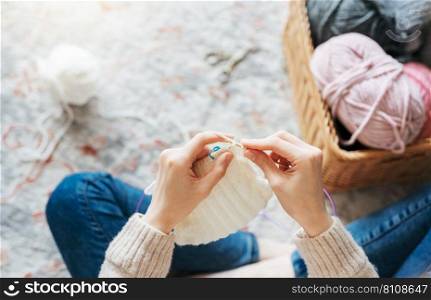 Young woman knitting warm scarf at home