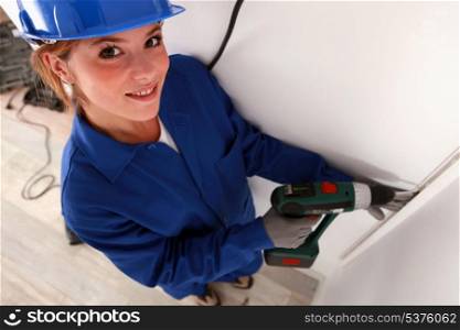 Young woman laborer using drill