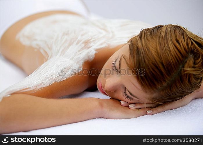Young woman laid with cream on her back