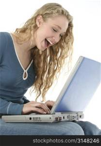 Young woman laughing and typing on laptop. Shot in studio over white.