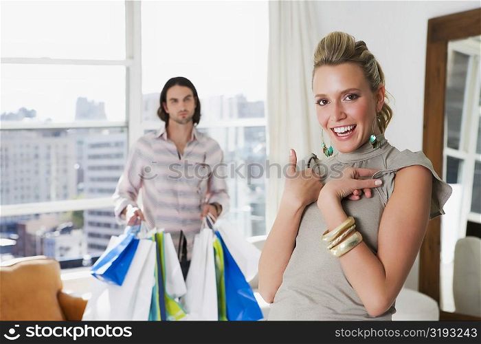 Young woman laughing with a young man holding shopping bags behind her