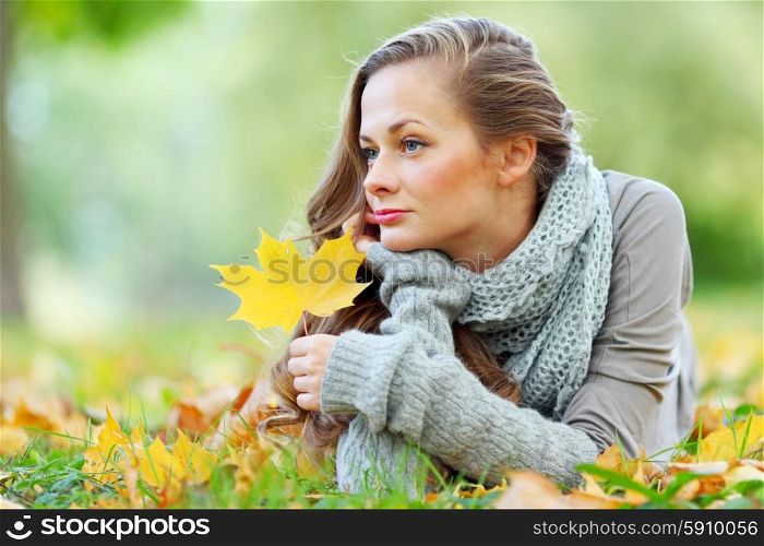 Young woman laying down on the ground in autumn park. Woman in autumn park