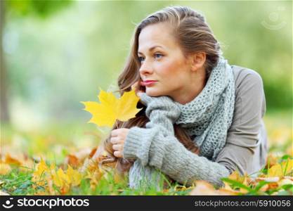 Young woman laying down on the ground in autumn park. Woman in autumn park