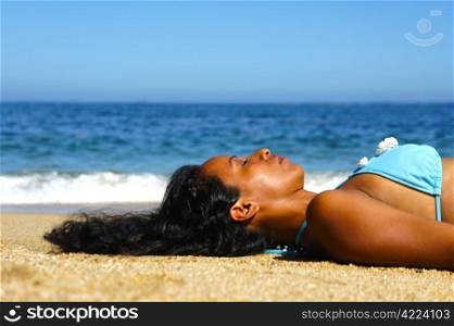 Young woman laying on beach sun tanning.