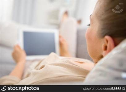 Young woman laying on divan with tablet pc . rear view