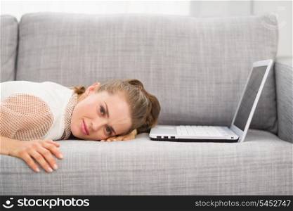 Young woman laying on sofa with laptop