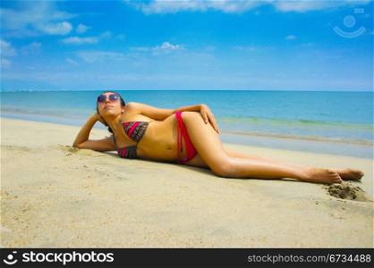 Young woman laying on the beach sun tanning.