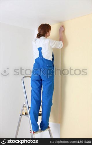 Young woman laying wall paper