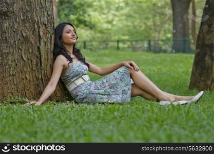Young woman leaning against a tree