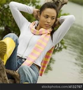 Young woman leaning against a tree stump looking away