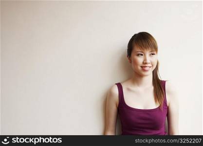 Young woman leaning against a wall and smiling