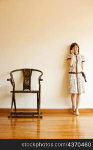 Young woman leaning against a wall and talking on a mobile phone