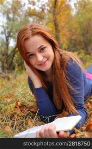 Young Woman Leaning Book outdoors in autumn park