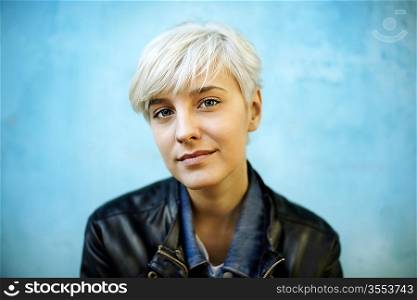 Young woman leaning on grungy blue wall. Selective focus