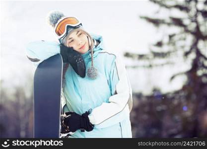 Young woman leaning on her snowboard, she’s looking away and smiling  copy space, close up, lens flare
