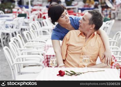 Young woman leaning over a mature man at a sidewalk cafe