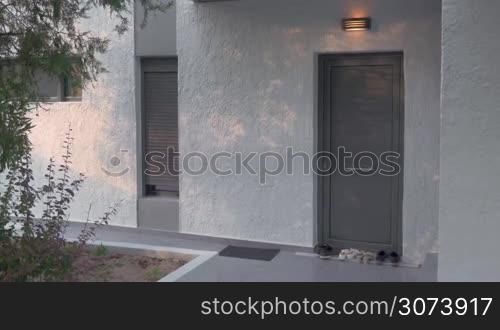 Young woman leaving home at sunset. She putting on the shoes at the doorstep and walking away. Rent of houses, villas and hotels for holiday