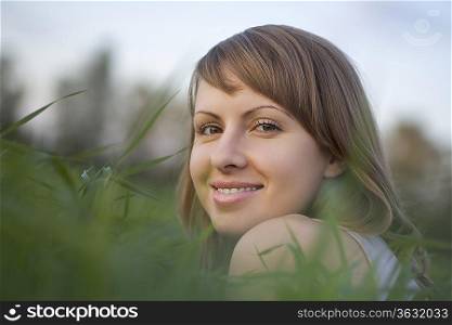 Young woman lies in a field of grass