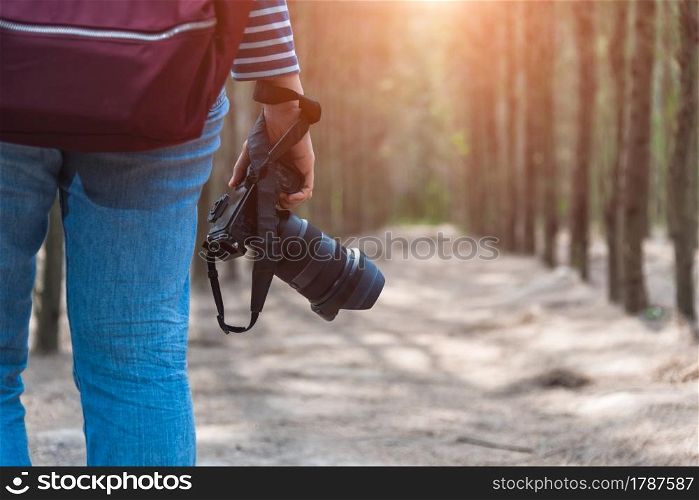 Young woman lifestyle using DSLR camera photographer travel taking photo in forest nature park and backpack and copy space