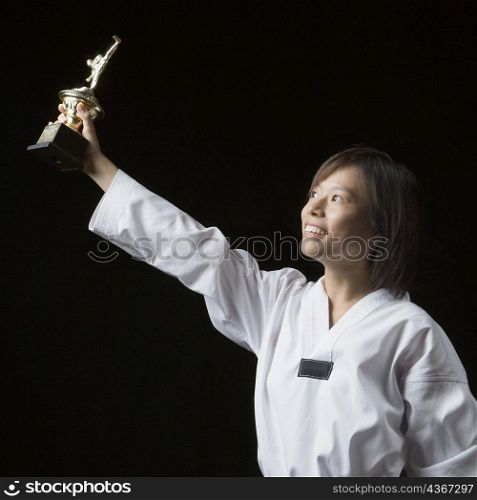 Young woman lifting a trophy and smiling