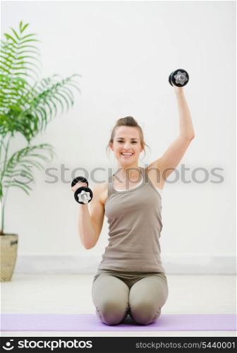 Young woman lifting dumb-bells
