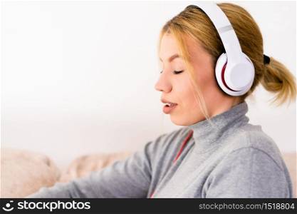 Young woman listen to the music via headphones, enjoying at home hotel