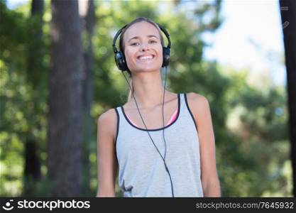 young woman listening music with headphone in nature