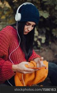 Young woman listening music with her headphones in the forest