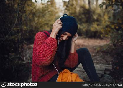 Young woman listening music with her headphones in the forest