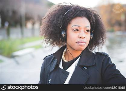 Young woman listening to headphones in park at Lake Como, Italy
