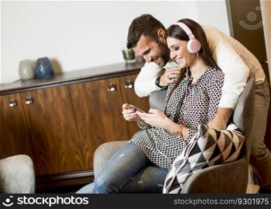 Young woman listening to music from a mobile phone using the handset while the young man hugging