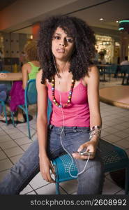 Young woman listening to music in mall food court