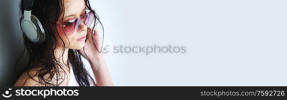 Young woman listening to music on headphones enjoying a dance. Closeup portrait of girl on light background with copy space. Woman listening music in headphones