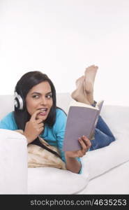 Young woman listening to music while reading