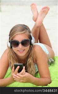 Young woman listening to music while tanning at the beach