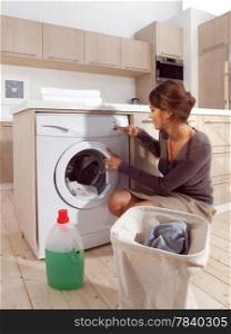 Young woman loading the washing machine in room