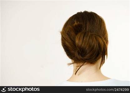 Young woman long brown hair wrapped in bun. Back view. Girl with brown long hair tied in bun