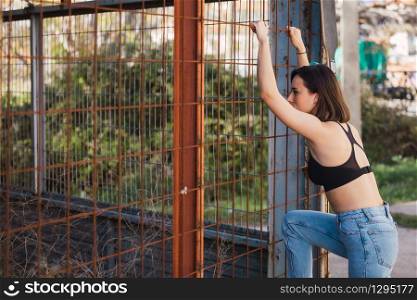 Young woman look inside through a fence in a ancient industrial street