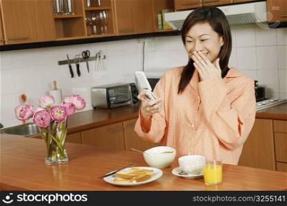 Young woman looking at a mobile phone at a kitchen counter