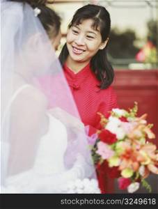 Young woman looking at another woman in the wedding dress and smiling