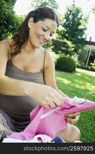 Young woman looking at baby clothes and smiling