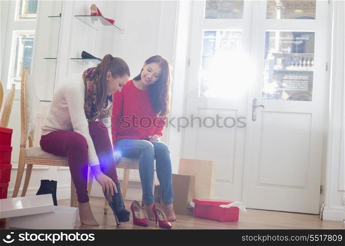 Young woman looking at friend trying on footwear in store