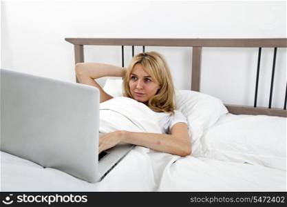 Young woman looking at laptop in bed