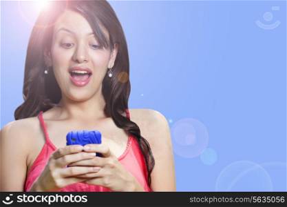 Young woman looking at mobile phone , mouth open