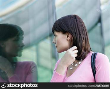 Young woman looking at reflection of self in building window