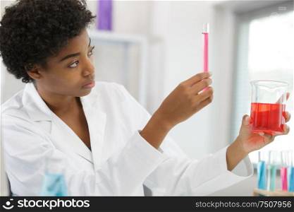 young woman looking at test tube in a chemical lab