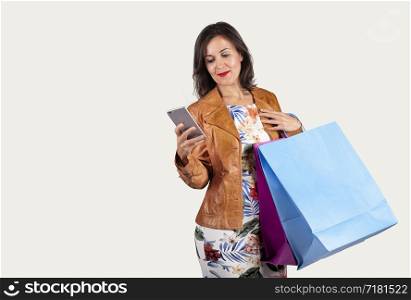young woman looking at the mobile and with some shopping bags on a white background