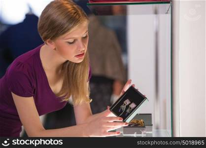 Young woman looking at the shop showcase and taking accessories to look at it closer