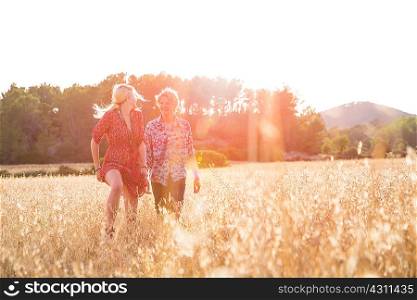 Young woman looking back at boyfriend running in wheat field, Majorca, Spain