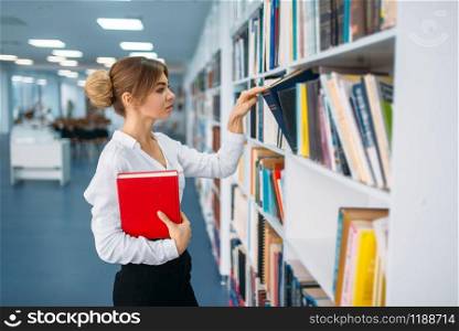 Young woman looking book at the shelf in library. Female person in reading room, knowledge depository